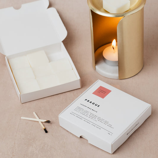 Candle mulled wine scented wax melts in packaging with matches and a lit candle on a beige surface