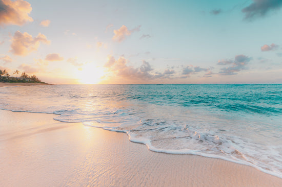 Golden sandy beach with clear blue waters and sun in Byron Bay, Australia