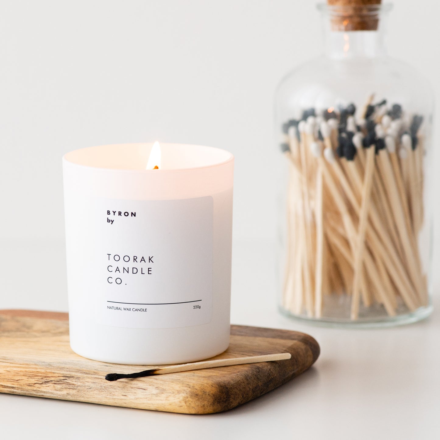 BYRON natural wax candle placed on wooden surface with matches beside it