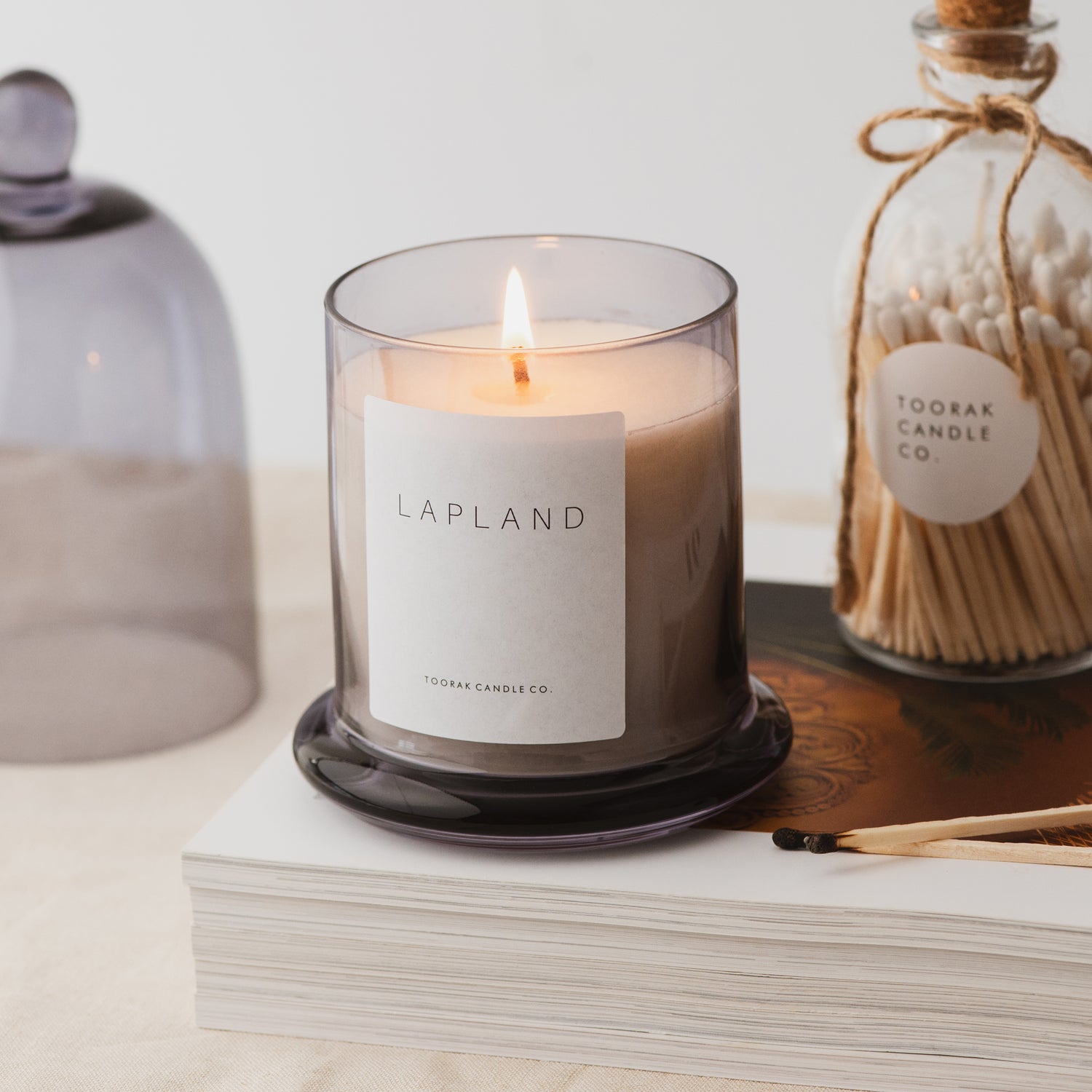 Lit Lapland luxury natural wax cloche candle with matched and books 
