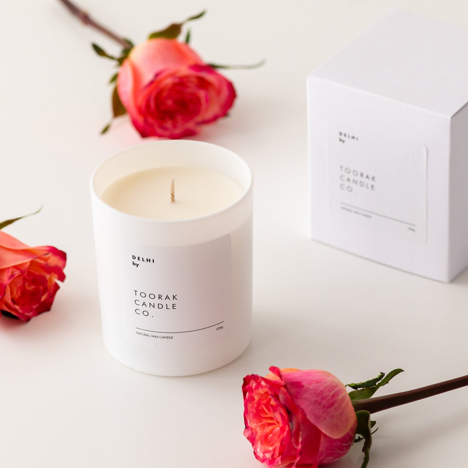Unlit DELHI natural wax candle with box, with three pinkish red roses surrounding them